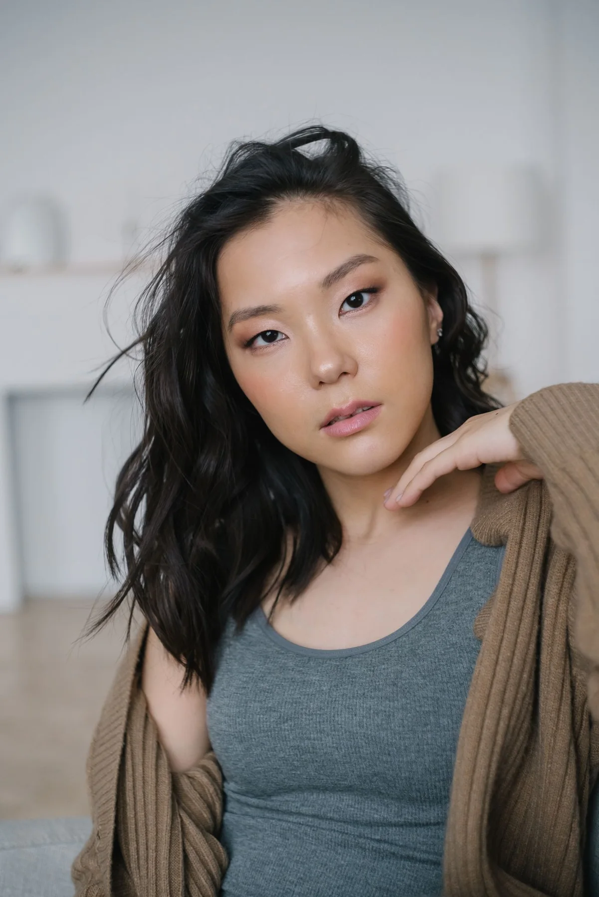 A woman wearing a cardigan over a tank top indoors.