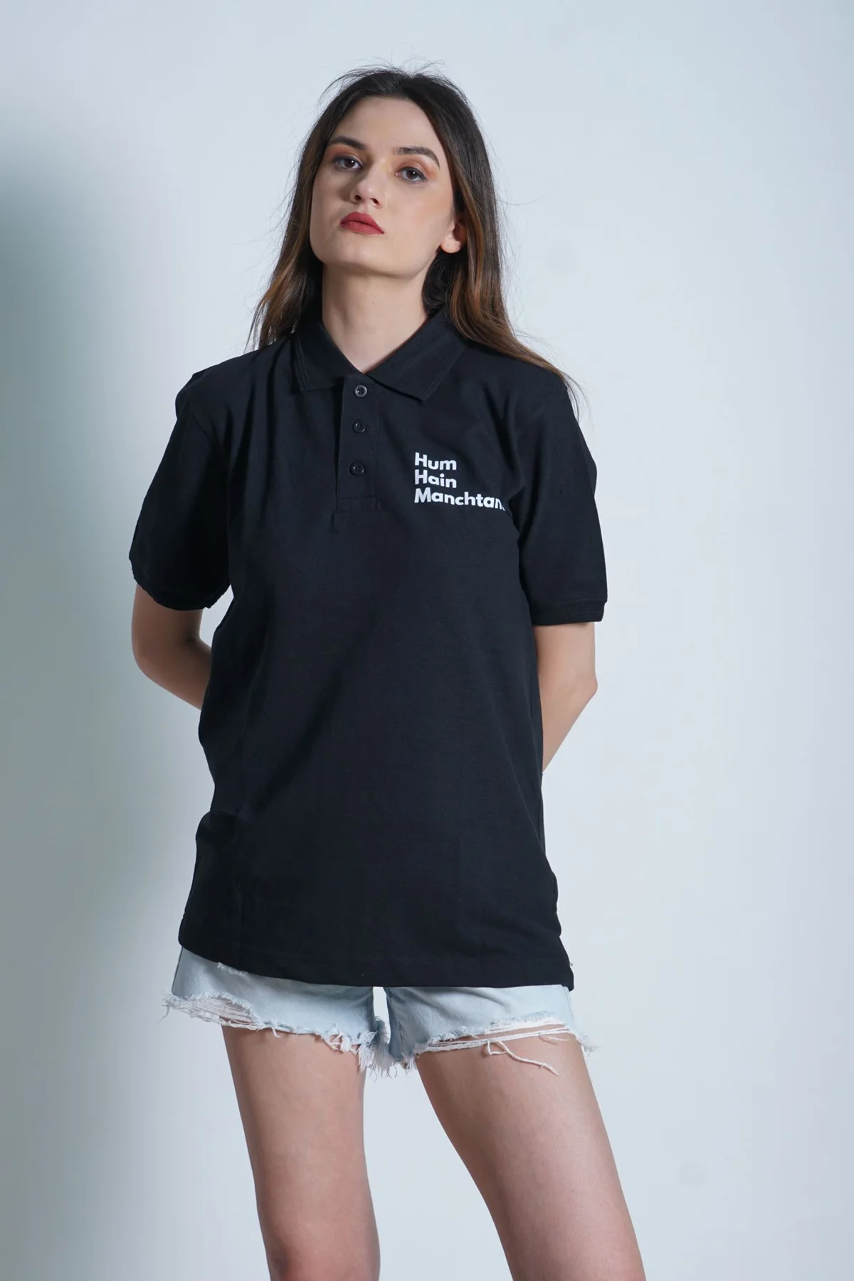 A woman wearing a black polo shirt in a studio.