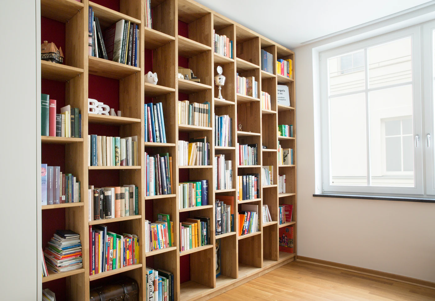 Tall wooden bookshelves filled with books beside a bright window.