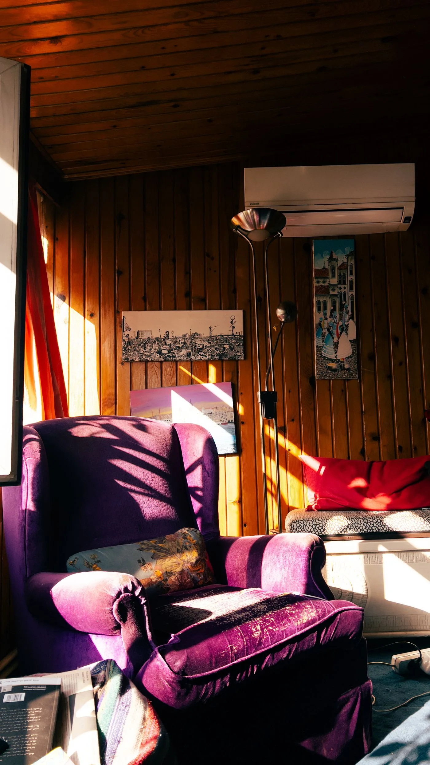 A purple upholstered armchair in a warmly lit room with wooden walls.