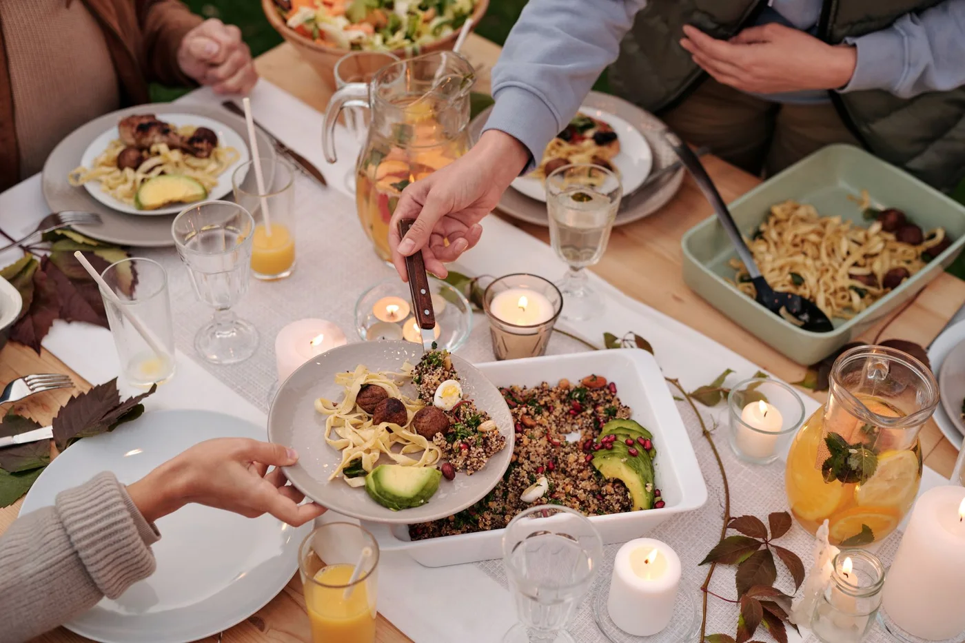 Several people sharing dishes and drinks around a dining table.