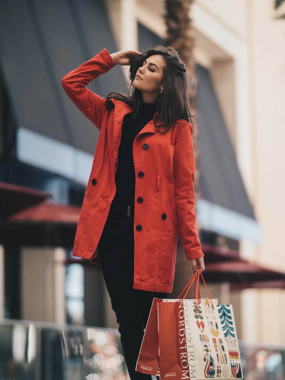 A woman in a red coat over dark clothing on a city street.
