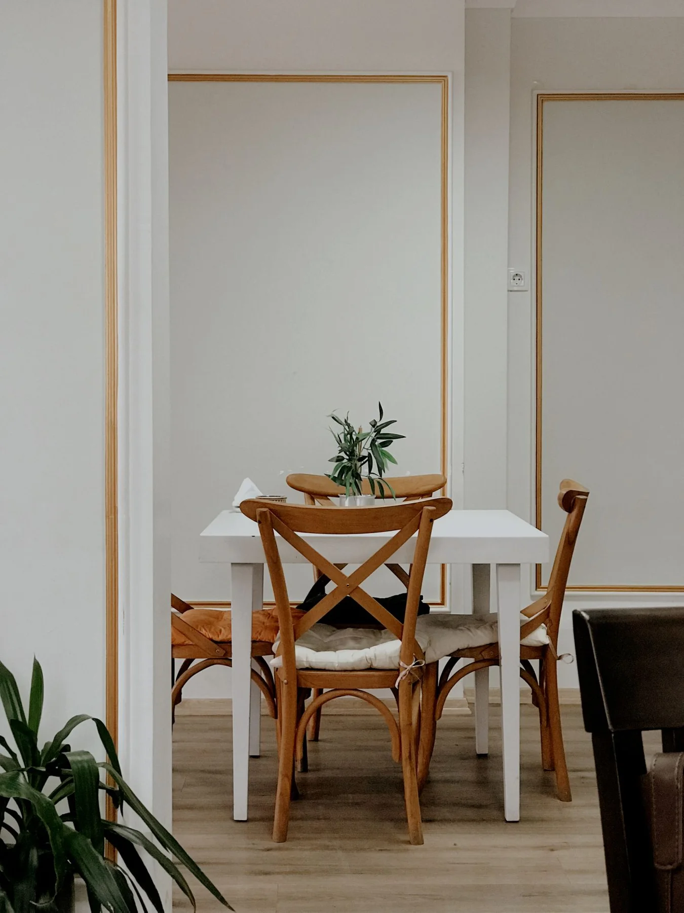 Wooden dining chairs around a white table in a light room.